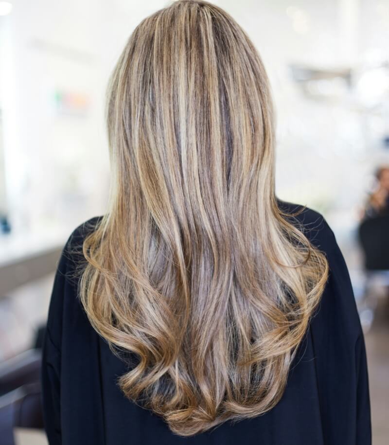 woman with new blonde hair extensions flowing down back