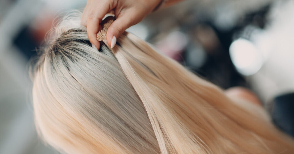 holding up blonde hair wefts to client's hair