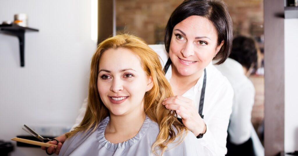 hair-stylist-talking-to-client-with-red-hair-about-style-1200-630 hairdresser standing behind client with red hair