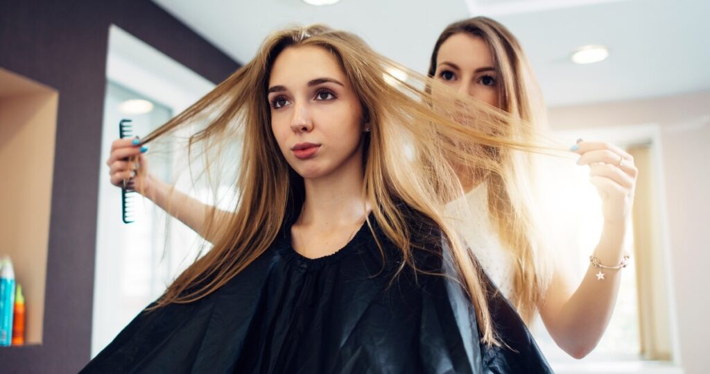 hairdresser-feeling-clients-hair-before-starting-to-work-1200-630 hair stylist coming through client's blonde hair
