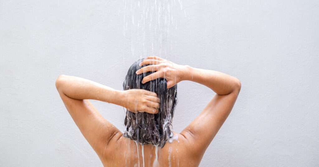 water falling from shower faucet washing soap from woman's hair