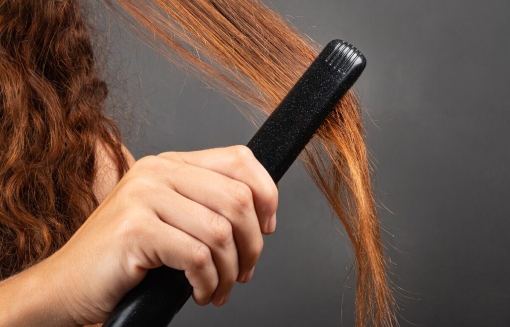 straightening-frizzy-red-hair-with-flat-iron flat iron going over red tangled hair