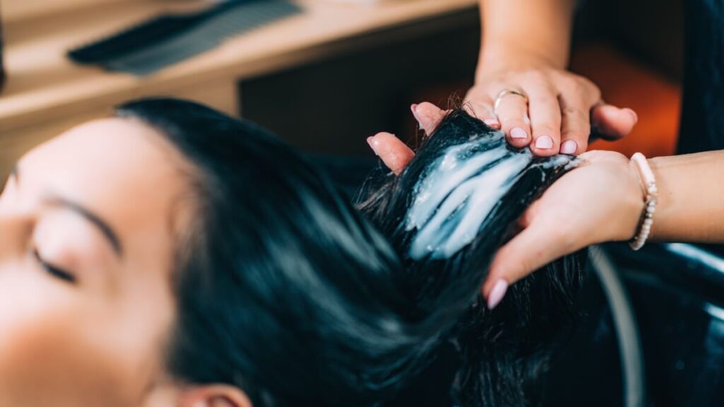 hair stylist applying conditioner to hair at salon