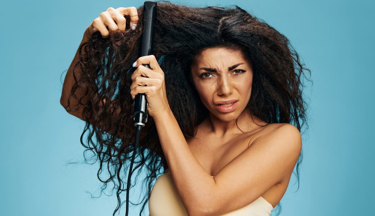 woman with angry look as she tries to straighten curly hair