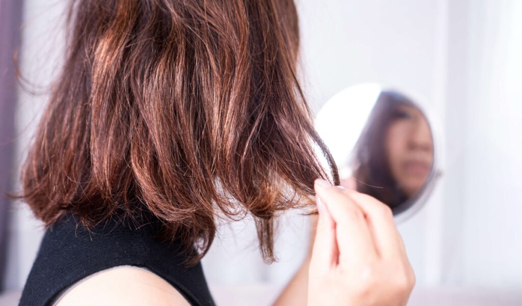 woman with short dry hair looking at self in the mirror