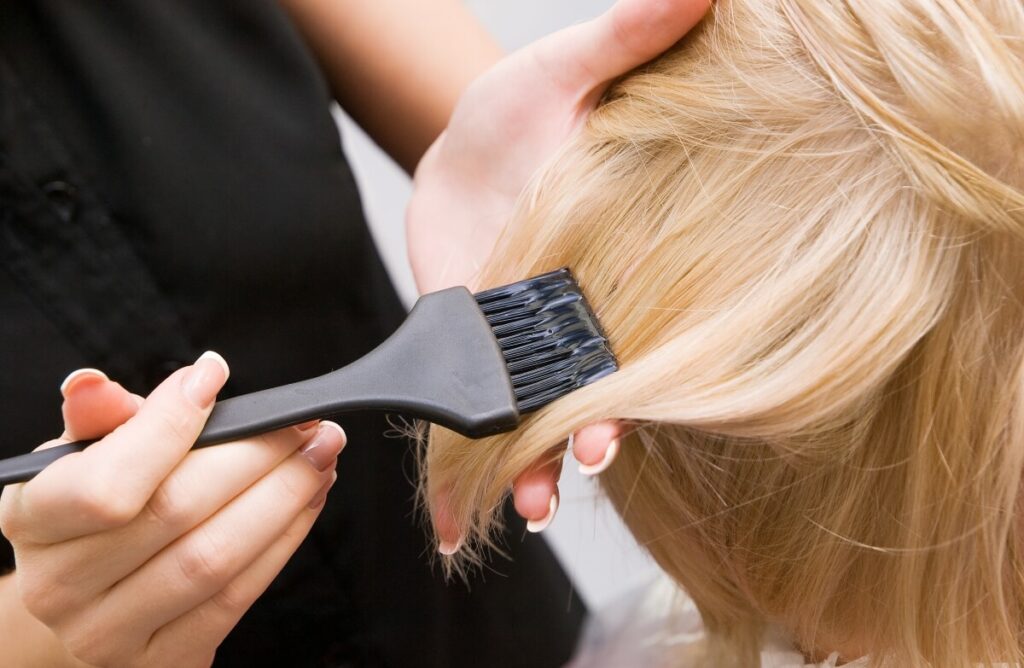 brushing-dye-onto-blonde-hair-at-hair-salon applying dye to blonde hair