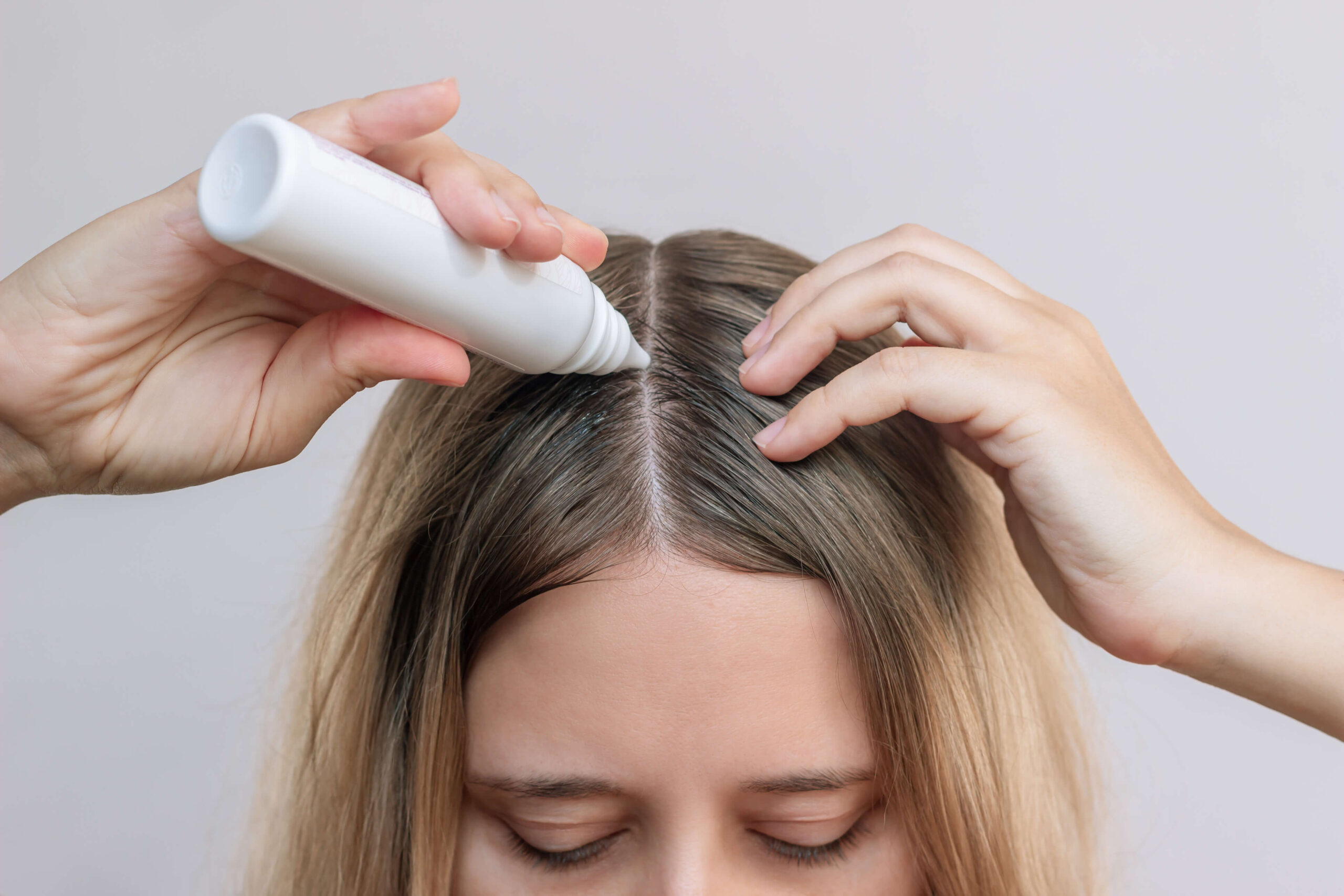 woman applying chemicals to hair roots