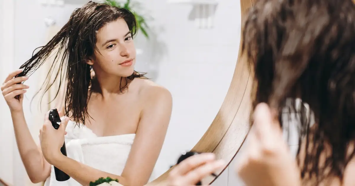 woman applying product to hair after shower